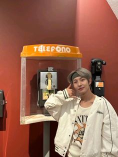 a woman standing in front of a pay phone booth with her hand on her head