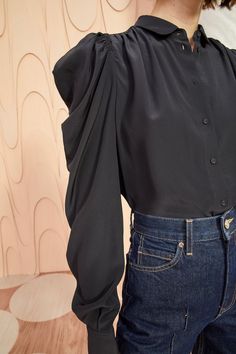 The season-favorite Dari Blouse is made from soft silk crepe de chine in deep noir. This elegant workwear style has a Peter Pan collar, draped sleeves, a centered button closure, and is finished with a buttoned cuff. Length of blouse is 25-inches from highest shoulder point to hem.   Composition: 100% Silk   Style with Elegant Workwear, Black Silk Top, Nyc Boutiques, Draped Sleeves, Workwear Style, Silk Style, Short Loungewear, Drape Sleeves, Workwear Fashion