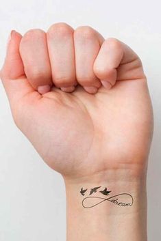 a woman's arm with a small tattoo on the wrist and two birds flying in the air