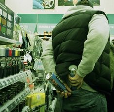 a man holding a can in his hands while standing next to a shelf filled with cans