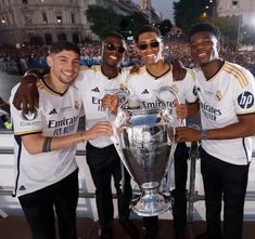 three soccer players pose with the trophy in front of an audience at a sporting event