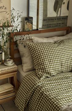 a bed with gingham sheets and pillows on top of it next to a wooden table