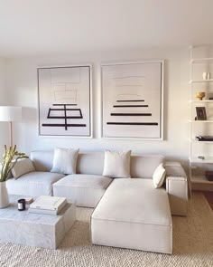 a living room filled with white furniture and paintings on the wall above it's couches