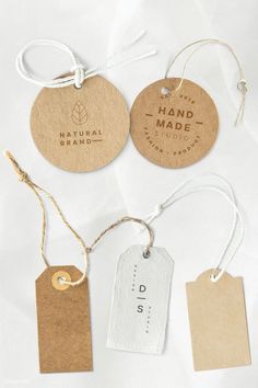 four tags with the words hand made hanging from strings and twine on white background