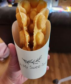 a person holding a cup filled with fried food