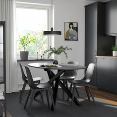 a dining room table and chairs in front of a window with plants on the windowsill