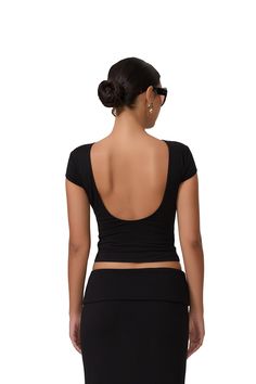 the back of a woman wearing a black skirt and cropped top with cut outs