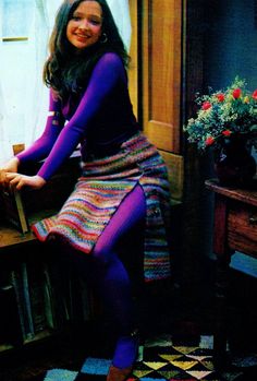 a woman sitting on top of a wooden table next to a window