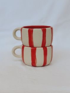 two red and white striped mugs sitting on top of each other