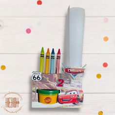 a set of crayons and markers with cars on them next to some confetti