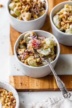 three white bowls filled with food on top of a wooden cutting board next to a spoon