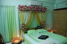 a green bed with flowers on the headboard and curtained windows in the background