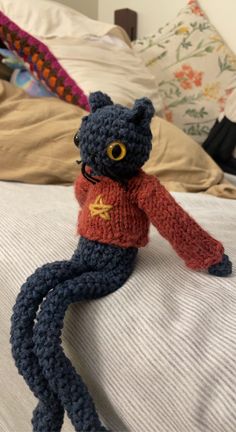 a crocheted cat sitting on top of a bed