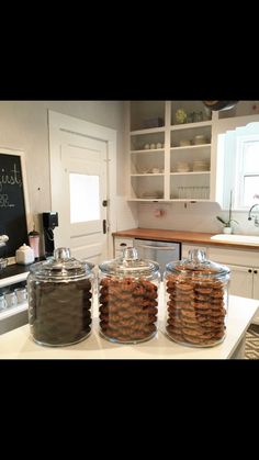 three jars filled with cookies sitting on top of a counter