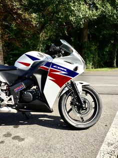 the motorcycle is parked on the side of the road in front of some trees and bushes