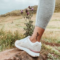 a woman's foot with a small flower tattoo on her left ankle and right leg