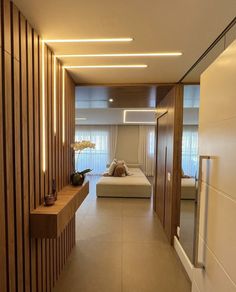 a long hallway leading to a bed in a room with wooden walls and flooring