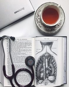 an open book with a stethoscope next to it and a cup of tea