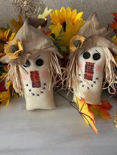 two scarecrow heads sitting next to each other on a table with sunflowers