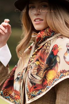 Woman wearing a colorful pheasant-patterned scarf and a wide-brimmed hat.