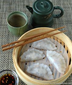 some dumplings are in a basket with chopsticks next to it and a cup of tea