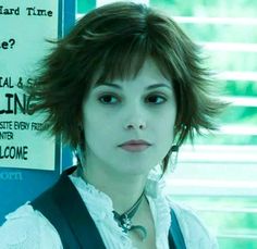 a woman with short hair standing in front of a sign