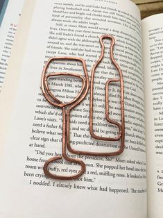 an open book with a pair of copper scissors on top of it next to a metal hook that is shaped like a stethosk