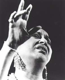 a black and white photo of a woman holding her hand up in the air while singing