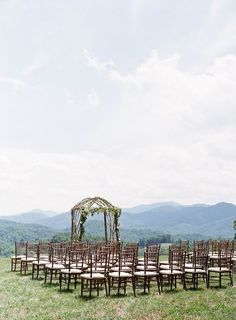 an outdoor ceremony set up with chairs and a gazebo in the distance, surrounded by mountains