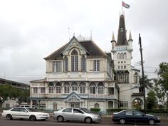 three cars are parked in front of an old building with a steeple on top