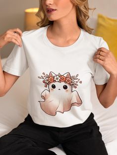 Get ready for spooky season with this adorable Floral Ghost Cat T-Shirt! Featuring a cute ghost cat adorned with a vibrant flower crown, this whimsical tee is perfect for Halloween and fall festivities. Made from high-quality materials, it's comfortable and stylish, making it a great addition to your seasonal wardrobe. Whether you're a cat lover or looking for a unique Halloween outfit, this shirt is sure to turn heads and spread smiles. Ideal for casual wear, parties, or as a fun gift for friends and family. Celebrate the spooky season in style! We utilize the authentic Bella Canvas 3001 brand, renowned for its UNISEX design, making it one of the most sought-after shirts in the market. Prior to placing an order, kindly refer to our size chart. It can be located in both the listing's image White Cat Print T-shirt For Halloween, Kawaii Halloween Short Sleeve T-shirt, Kawaii Short Sleeve Halloween T-shirt, Kawaii Halloween Graphic Print Tops, Cute White Tops For Halloween, Halloween White T-shirt With Cat Print, White Cat Print T-shirt For Fall, White T-shirt With Cat Design For Fall, Cute Halloween Cartoon Print T-shirt