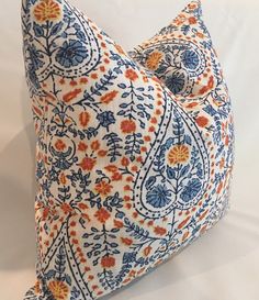 a blue and orange pillow on a white surface with an intricate design in the middle