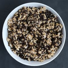 a white bowl filled with black and brown food on top of a dark countertop