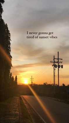 the sun is setting over an empty road with power lines and telephone poles in the distance