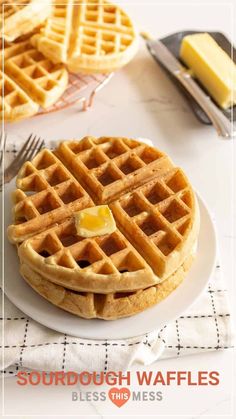 two waffles with butter on top sitting on a white plate next to silverware