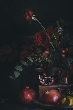 a still life with flowers, fruit and pomegranates on a table