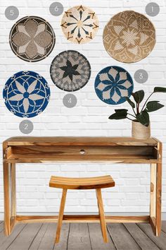 a wooden bench sitting in front of a white brick wall with several decorative plates on it