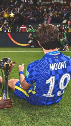 a man sitting on the ground with two trophies