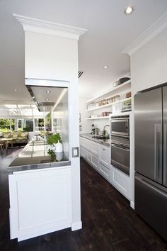 a large kitchen with white cabinets and stainless steel appliances in the center, along with dark wood flooring