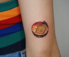 a woman's arm with a small tattoo of food on the left side of her arm