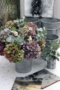 flowers are sitting in buckets on the ground next to some magazines and other items