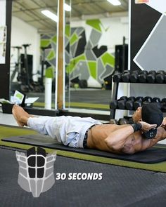 a man laying on top of a black mat in a gym