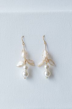 Lynlee earrings are the ultimate accessory to elevate your wedding day style. Featuring beautiful crystal pearls and a lovely lily flower detail, these earrings exude an air of timeless elegance that will draw all eyes to you. DETAILS ❁Handcrafted dip resin flowers with polarized white petals and glossy finish.  ❁Graceful design with dainty Swarovski crystal pearl details. ❁Designed and handmade in Canada. Worldwide shipping. ❁Beautifully gift wrapped in our signature packaging to store your ite Formal White Clip-on Flower Earrings, Delicate Pearl Charm Flower Earrings, Delicate Flower-shaped Earrings With Pearl Charm, White Flower-shaped Earrings With Pearl Charm, White Pearl Drop Clip-on Earrings For Wedding, Wedding Flower Earrings With Pearl Charm, Delicate White Bridal Earrings With Pearl Charm, Delicate Pearl Charm Flower Earrings For Wedding, Elegant Dangle Clip-on Flower Earrings