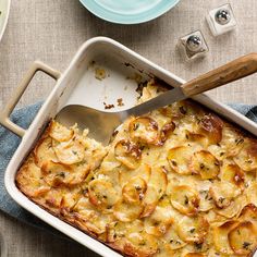 a casserole dish with potatoes in it and a spatula on the side