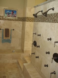 a bathroom with tiled walls and brown tile flooring, two shower heads are on the wall