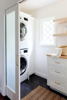 a washer and dryer in a white room with wood flooring on the side