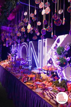 WONKA light up letters sitting behind a huge grazing table of pastries, candy, and savory snacks. Also features hundreds of colourful lollipops hanging from above. Willy Wonka Wedding Theme, Willy Wonka Centerpieces, Willy Wonka Food Ideas, Willy Wonka Party Ideas, Willy Wonka And The Chocolate Factory, Willy Wonka Themed Party, Chocolate Theme Party, Wonka Party Ideas, Willy Wonka Party Decorations