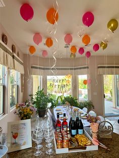 a table filled with lots of bottles of wine and balloons hanging from the ceiling above it