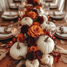 a long table with white pumpkins and flowers on it, along with other place settings