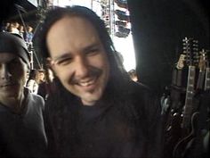 a man with dreadlocks smiles at the camera while standing next to another man